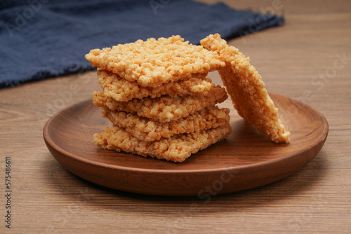 A plate of crispy rice is on the wooden table