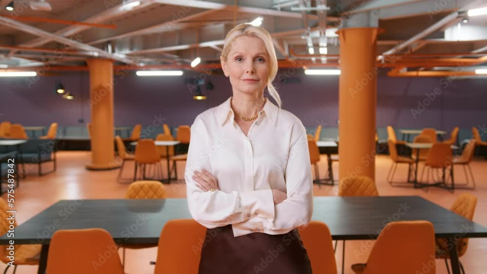 Caucasian 50s successful confident strong businesswoman manager lady boss 4K. Mature CEO leader woman in formal shirt posing crossing arms looking at camera in corporate loft office space background Caucasian 50s successful confident strong businesswoman manager lady boss 4K. Mature CEO leader woman in formal shirt posing crossing arms looking at camera in corporate loft office space background