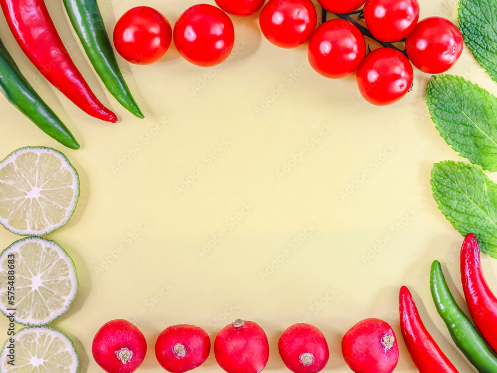 Red and green chili peppers, cherry tomatoes, mint leaves, radishes and lime slices on a yellow. Red and green chili peppers, cherry tomatoes, mint leaves, radishes and lime slices on a yellow.