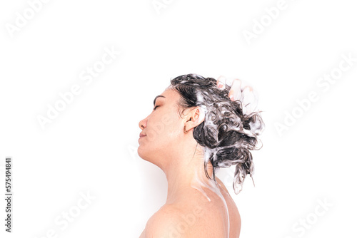 Lady washes her hair against a white background.