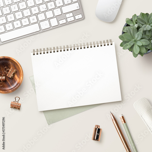 feminine desk / work space with office tools, succulent plant, and a blank open notebook / ring binder for your message on a bright cream colored background, square format, ideal for social media 
