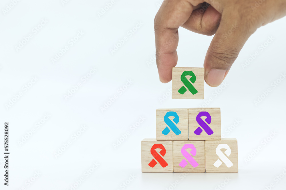 hand picking up wooden block cube with green color ribbon icon on white background.Liver, Gallbladders bile duct, kidney Cancer and Lymphoma Awareness month concept . hand picking up wooden block cube with green color ribbon icon on white background.Liver, Gallbladders bile duct, kidney Cancer and Lymphoma Awareness month concept .