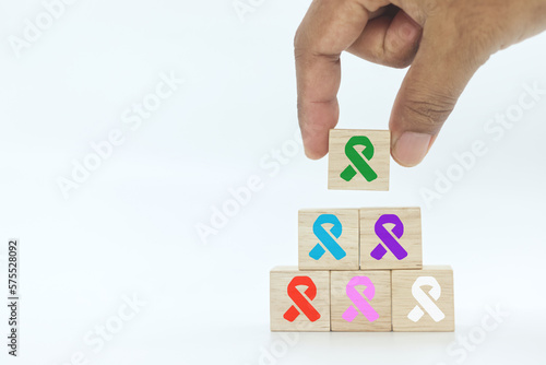 hand picking up wooden block cube with green color ribbon icon on white background.Liver, Gallbladders bile duct, kidney Cancer and Lymphoma Awareness month concept . 