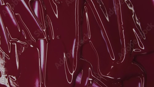 Red lipstick. Red background. Light and shine. Thick liquid. Smears of paint. Divorces on canvas. Decorative cosmetics. Вeauty salon advertisement. Wallpaper.