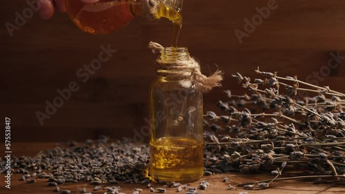 Small glass bottle with lavender oil. Handmade and craft cosmetics. Close up. Lavender flowers. Dry flowers. Wooden background. Air bubbles in the oil. Natural extract. Vintage. Old wooden table.