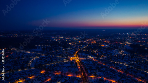 Flight over a city illuminated by a sunset flare. City lantern lights from above. A small town from above. Selective soft focus