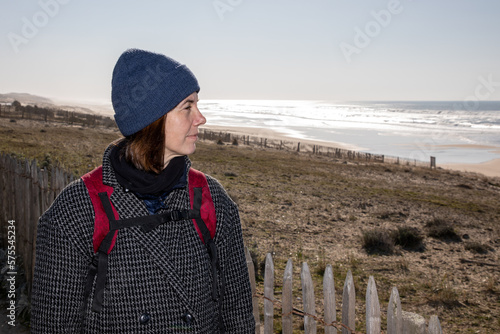 Woman winter day with cap backpack looking sea atlantic ocean on walk beach tour © OceanProd