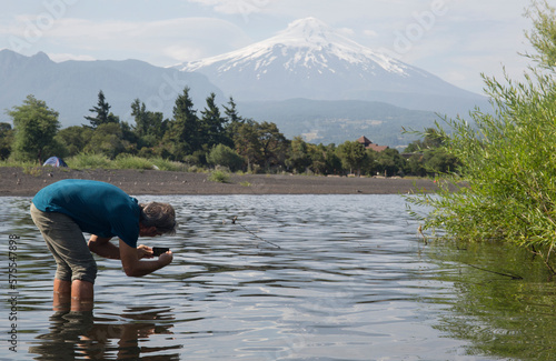 Man takes smart phone pic across lake, Villarica volcano photo