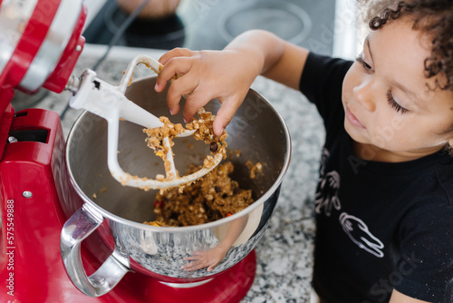 Adorable toddler sneaking a bite of the cookie dough photo