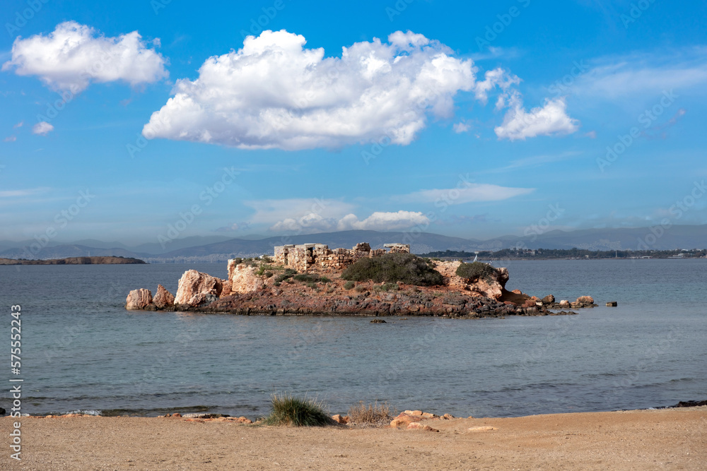 Greece Kavouri Voula. Small islet with stone ruins in sea water during low tide phenomenon.