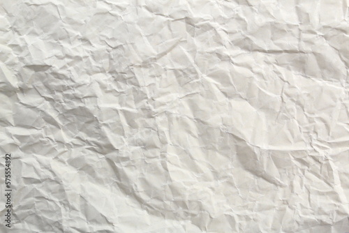 Soft crumpled sheet of light-colored paper. Abstract texture.	