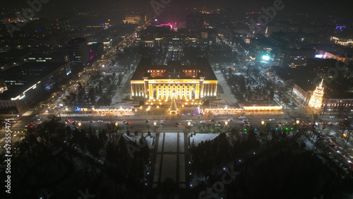 A large Christmas tree in the lights on the square. Top view from the drone on the street with cars and people, a bright building in garlands, various decorations for the new year. Almaty, December © SergeyPanikhin