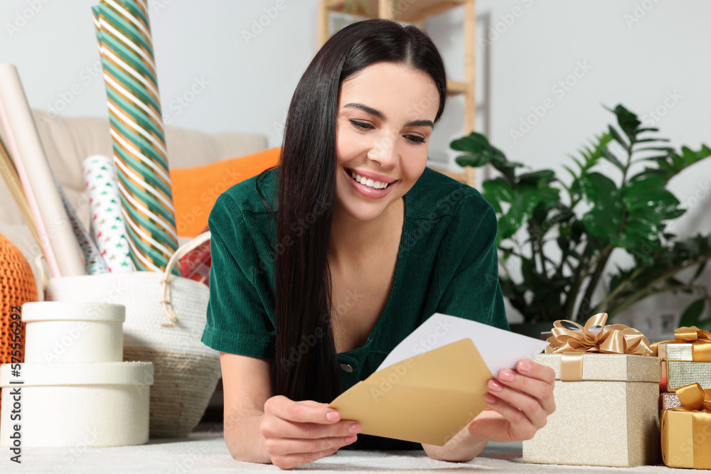 Happy woman reading greeting card on floor in living room Happy woman reading greeting card on floor in living room
