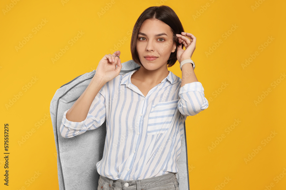 Woman holding garment cover with clothes on yellow background. Dry-cleaning service Woman holding garment cover with clothes on yellow background. Dry-cleaning service
