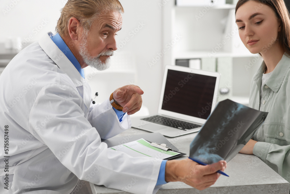 Orthopedist showing X-ray picture to patient in clinic Orthopedist showing X-ray picture to patient in clinic