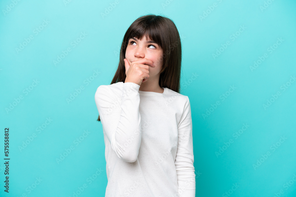Little caucasian girl isolated on blue background having doubts and with confuse face expression Little caucasian girl isolated on blue background having doubts and with confuse face expression