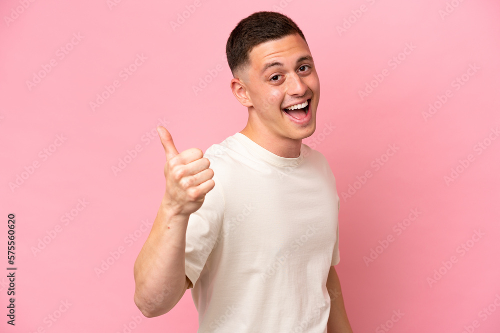 Young Brazilian man isolated on pink background with thumbs up because something good has happened Young Brazilian man isolated on pink background with thumbs up because something good has happened