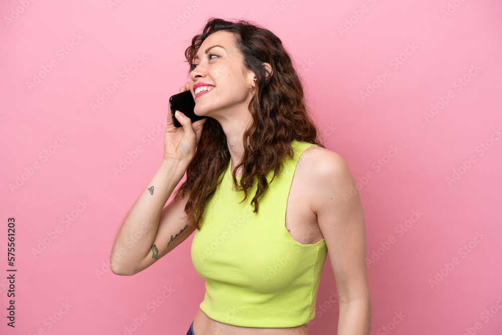 Young caucasian woman isolated on pink background keeping a conversation with the mobile phone Young caucasian woman isolated on pink background keeping a conversation with the mobile phone