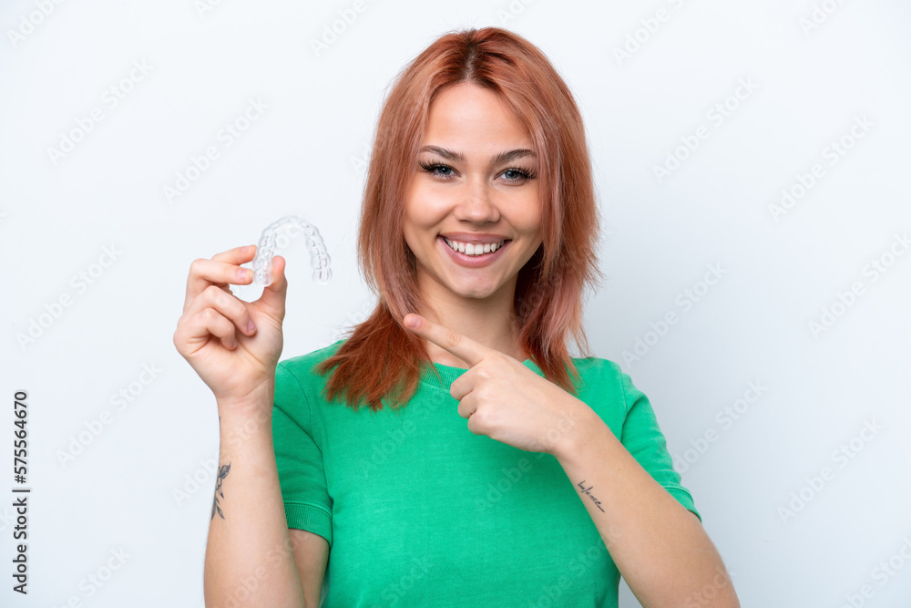 Young Russian girl holding invisible braces isolated on white background and pointing it Young Russian girl holding invisible braces isolated on white background and pointing it
