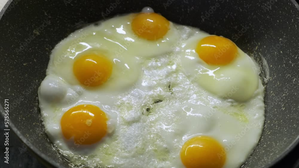 Close-up of eggs frying on a black pan. Cooking breakfast in the morning concept. Close-up of eggs frying on a black pan. Cooking breakfast in the morning concept.