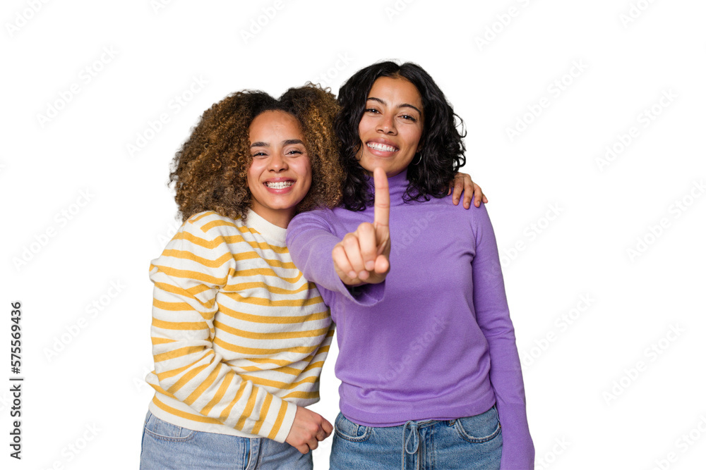 Two female friends isolated in studio showing number one with finger. Two female friends isolated in studio showing number one with finger.
