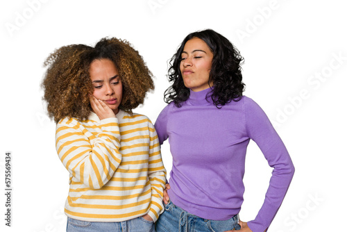 Two female friends isolated in studio touching back of head, thinking and making a choice. photo
