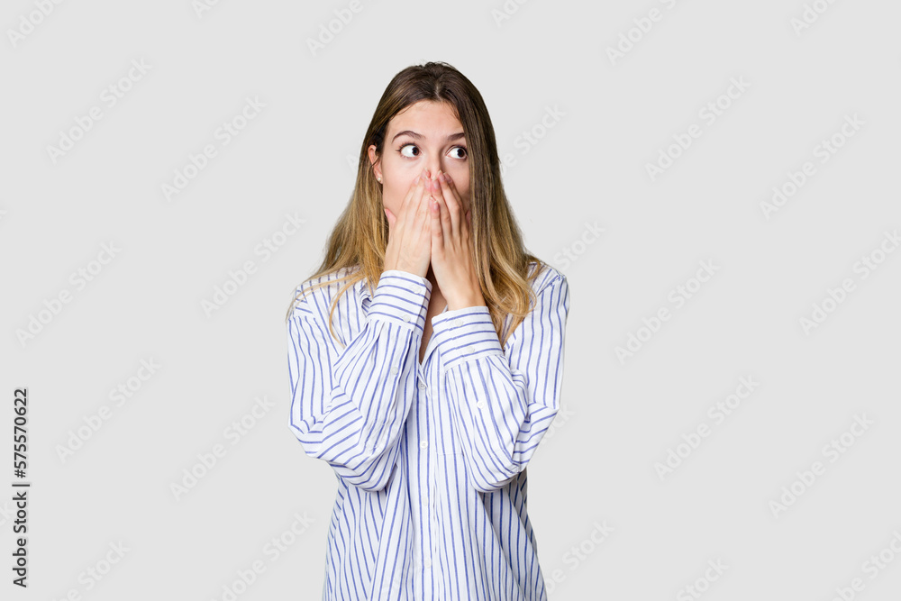 Young blonde posing for a portrait isolated, exuding natural beauty and radiance thoughtful looking to a copy space covering mouth with hand. Young blonde posing for a portrait isolated, exuding natural beauty and radiance thoughtful looking to a copy space covering mouth with hand.