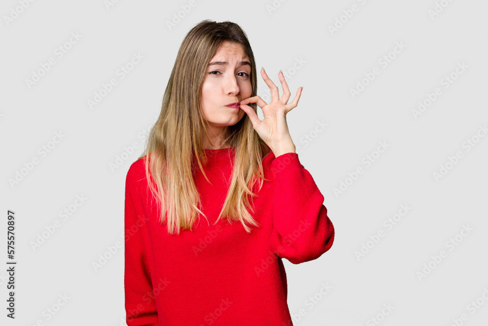 Young blonde posing for a portrait isolated, exuding natural beauty and radiance with fingers on lips keeping a secret. Young blonde posing for a portrait isolated, exuding natural beauty and radiance with fingers on lips keeping a secret.