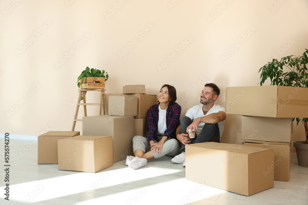 Happy couple with takeaway coffee resting on floor in new apartment. Moving day Happy couple with takeaway coffee resting on floor in new apartment. Moving day