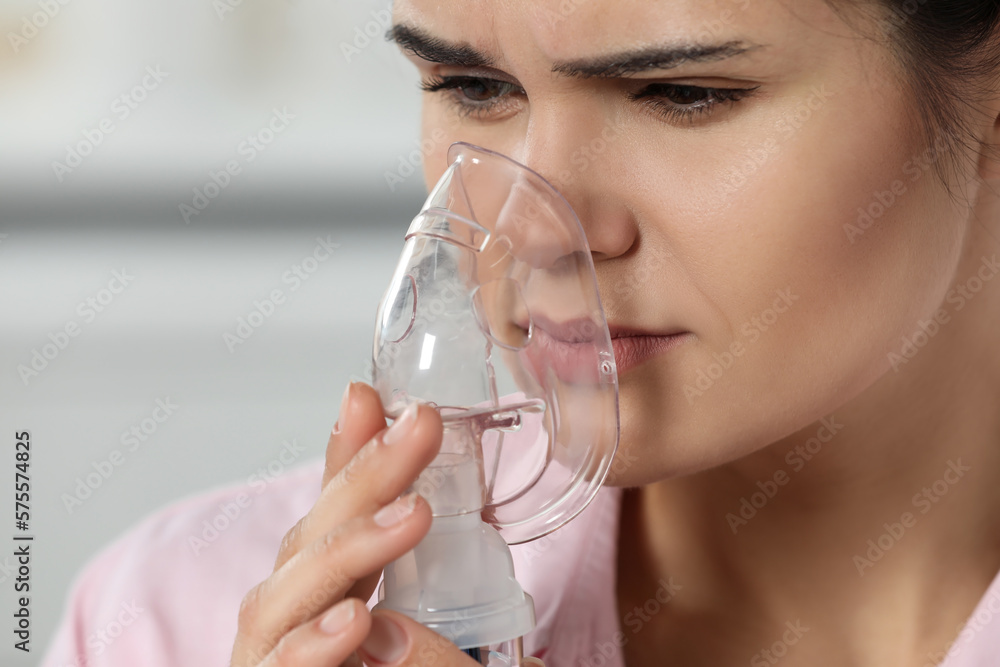 Sick young woman using nebulizer on blurred background, closeup. Space for text Sick young woman using nebulizer on blurred background, closeup. Space for text