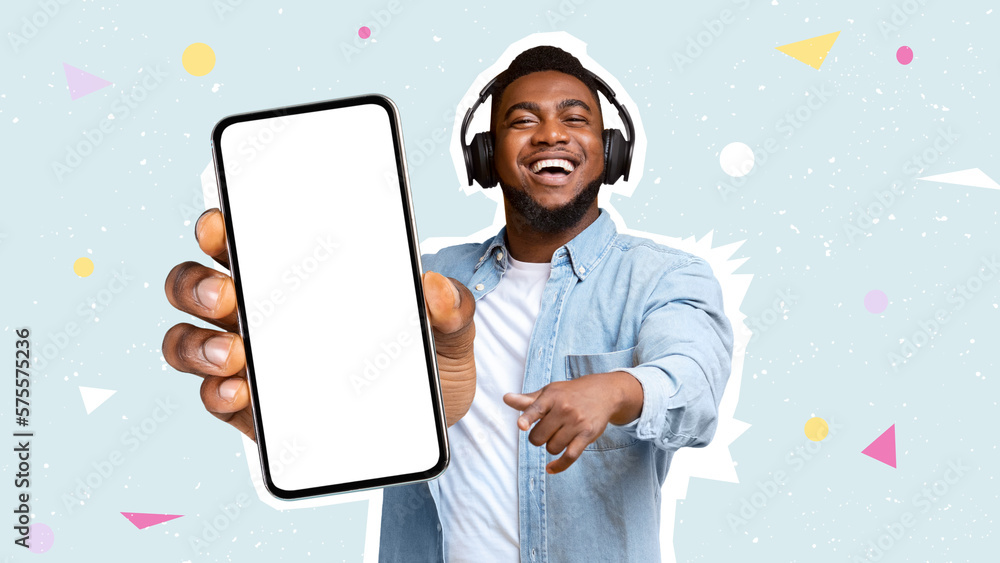 Happy black man using headphones, showing smartphone, mockup - obrazy, fototapety, plakaty 