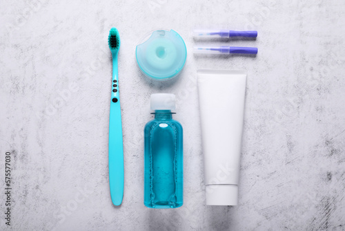 Flat lay composition with dental floss and different teeth care products on light grey textured table