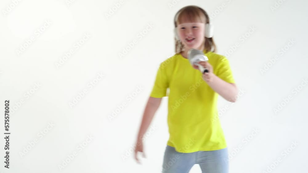 Young girl with down syndrome holds a microphone in her hands and sings a song isolated on white background. World down syndrome day background. Down syndrome awareness concept. Young girl with down syndrome holds a microphone in her hands and sings a song isolated on white background. World down syndrome day background. Down syndrome awareness concept.