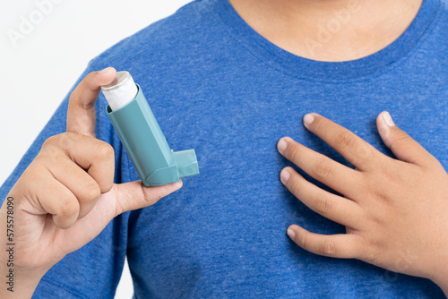 Asian boy using blue asthma inhaler for relief asthma attack. Medicinal products are used to prevent and treat asthma attacks and shortness of breath causing asthma or COPD, health care concept, photo