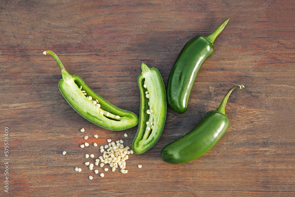 Fresh green jalapeno peppers and seeds on wooden table, flat lay Fresh green jalapeno peppers and seeds on wooden table, flat lay