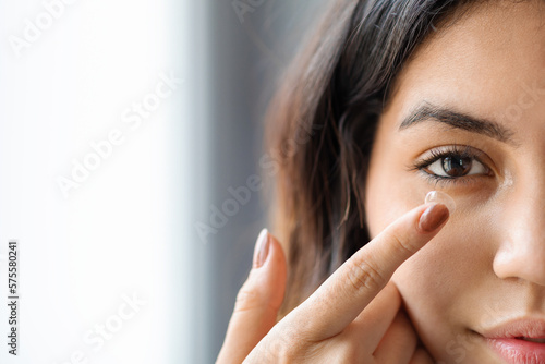 Ophthalmology Care Concept. Young arab woman putting contact lens in her eye