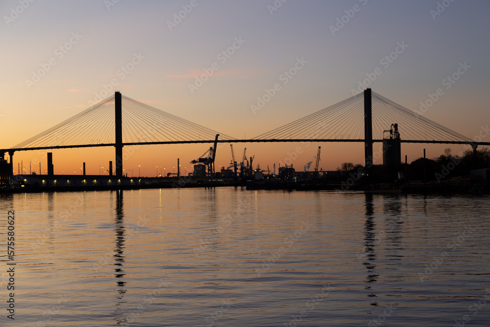 The 1991 cable-stayed Talmadge Memorial Bridge over the Savannah River seen in silhouette during a golden hour sunset