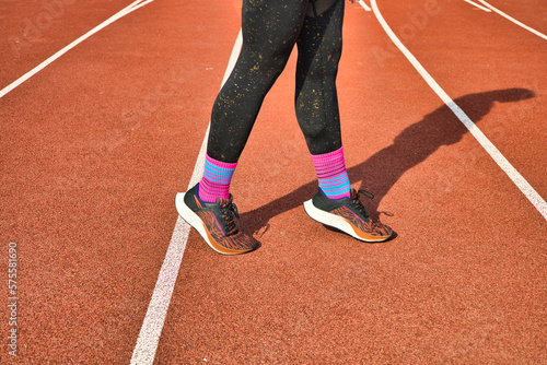 A hardy girl runner does an exercise on her legs. A man participating in a marathon, long distance running. Fitness and sport theme