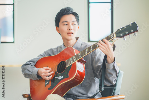 Foto 自宅でアコースティックギターを弾く若い男性
