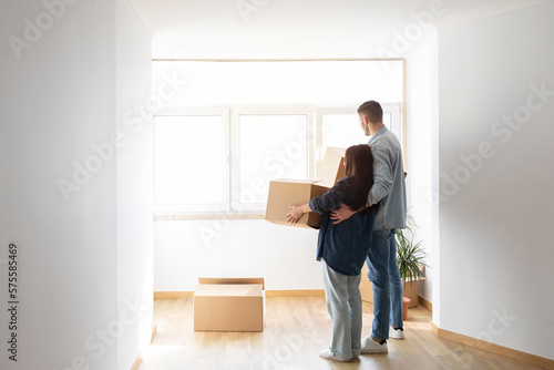 Real Estate. Couple With Cardboard Boxes In Hands Standing In New Home © Prostock-studio