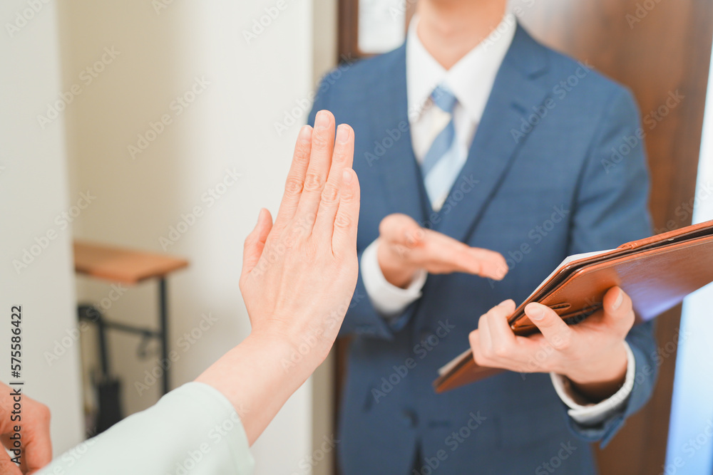 訪問販売を断る主婦と若い営業マンの男性 訪問販売を断る主婦と若い営業マンの男性