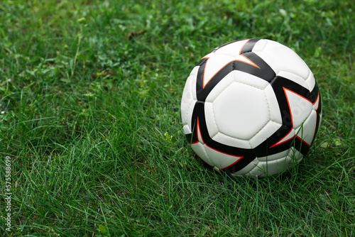 New soccer ball on fresh green grass outdoors, space for text