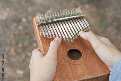 Girl holding play thumb piano or kalimba musical instrument.