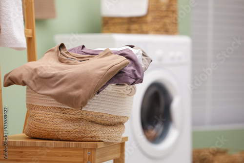 Laundry basket filled with clothes on chair in bathroom, closeup. Space for text