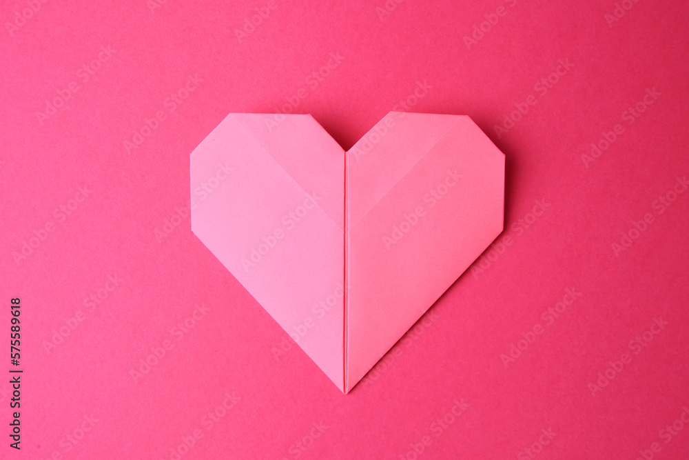 Paper heart on pink background, top view. Origami art