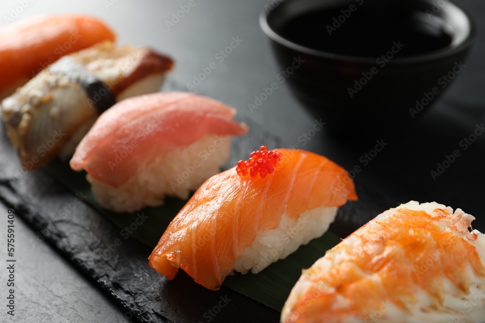 Serving board with delicious nigiri sushi and soy sauce on black table, closeup Serving board with delicious nigiri sushi and soy sauce on black table, closeup
