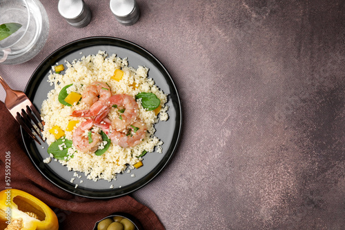 Tasty couscous with shrimps, bell pepper and basil on brown textured table, flat lay. Space for text