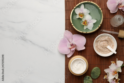 Composition with different spa products and flowers on white marble table, top view. Space for text