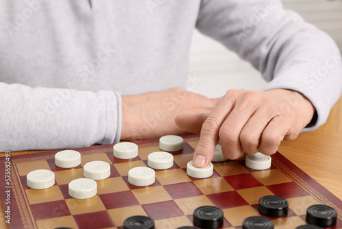 Playing checkers. Senior man thinking about next move at table, closeup