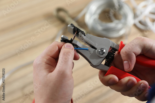 Professional electrician stripping wiring at wooden table, above view